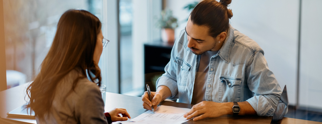Un jeune homme signe un contrat avec un conseiller bancaire