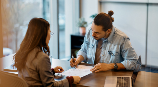 Un jeune homme signe un contrat avec un conseiller bancaire